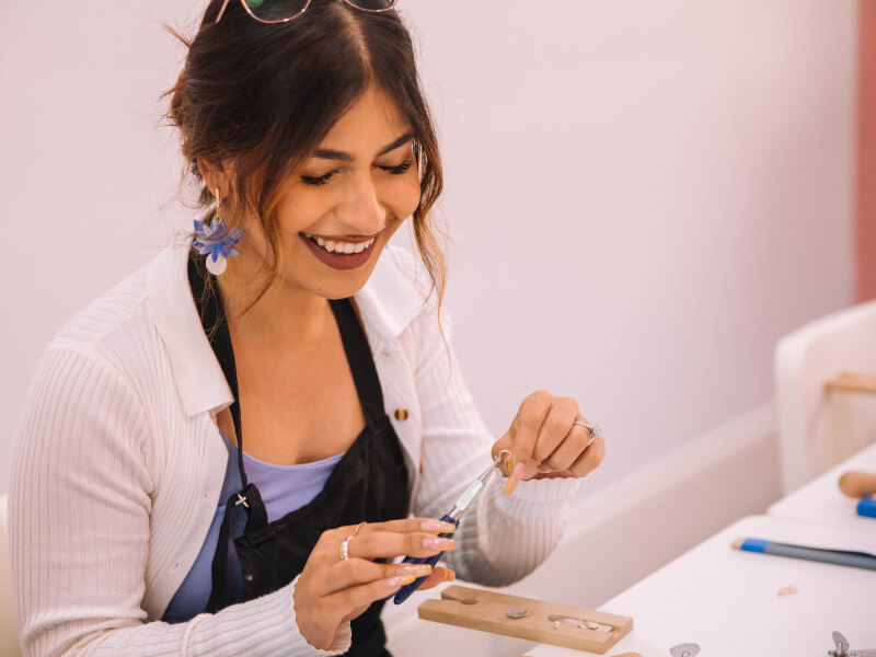A woman makes earrings at jewellery making experience she was gifted